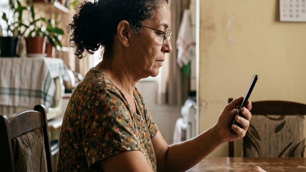 Aposentada conferindo o extrato do benefício no celular para identificar desconto não autorizado no INSS